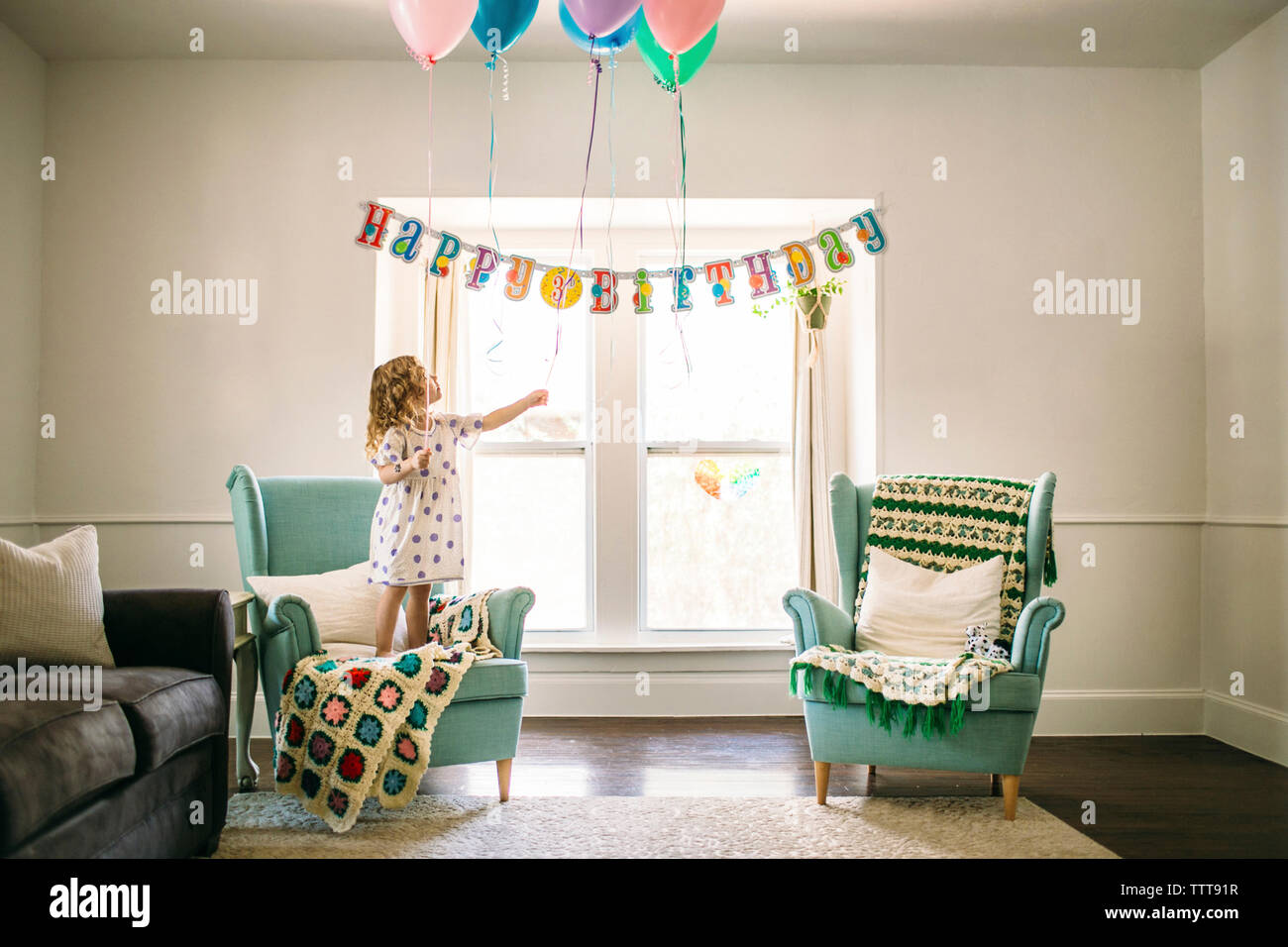 Girl decorating ballons dans le salon pour anniversaire Banque D'Images