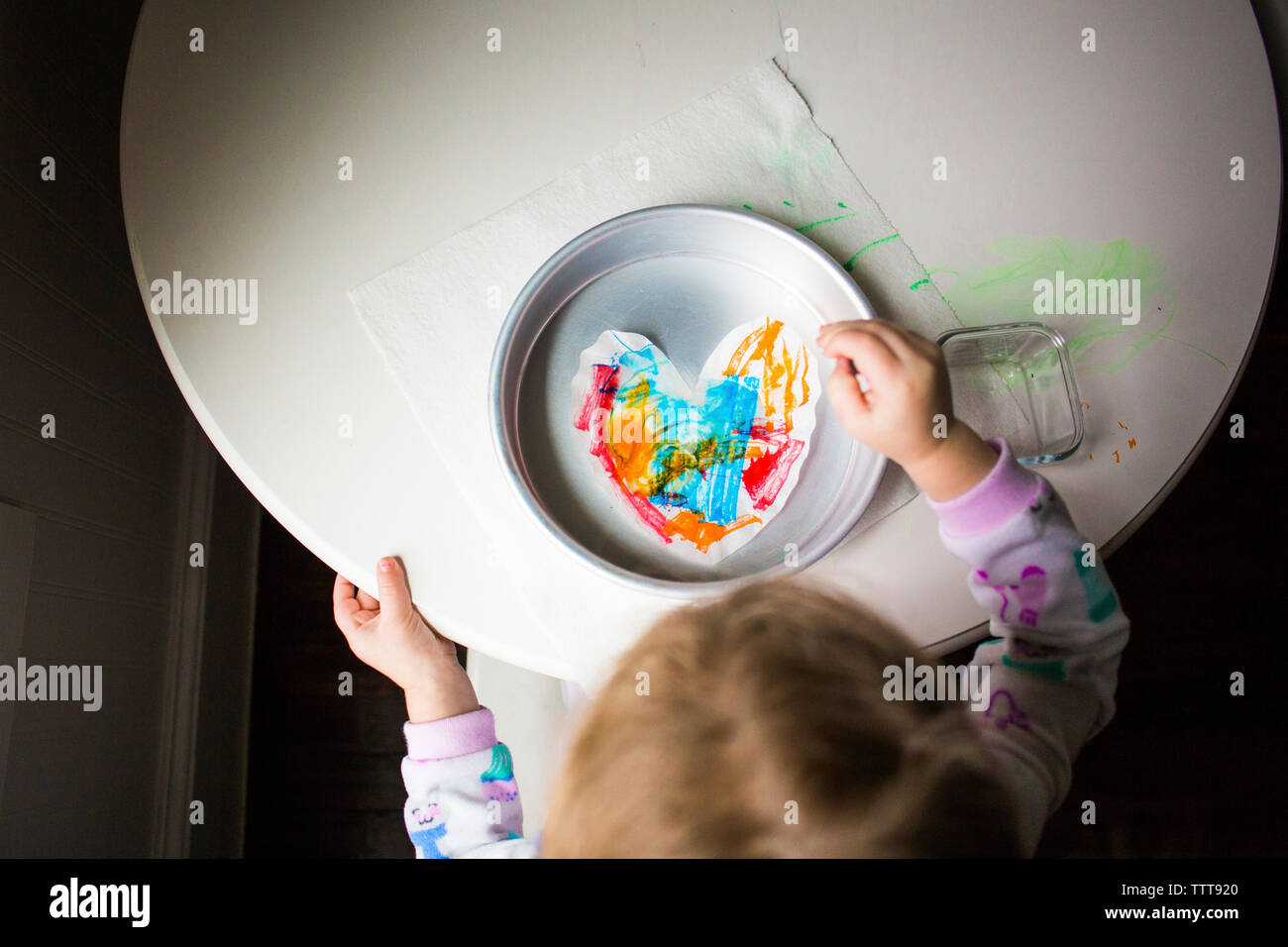 High angle view of girl coloring papier en forme de coeur dans le récipient sur la table Banque D'Images