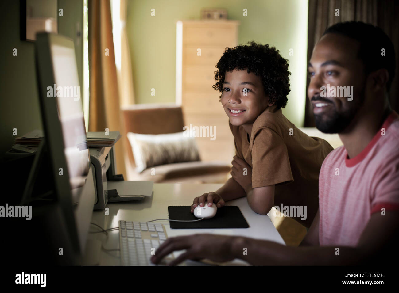 Père et fils à l'aide d'ordinateur tout en restant assis à la maison Banque D'Images