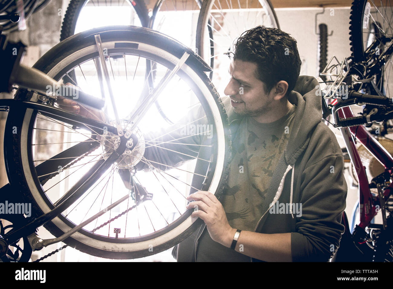 L'examen de la clientèle masculine des pneus de bicyclettes en étant debout dans le magasin Banque D'Images