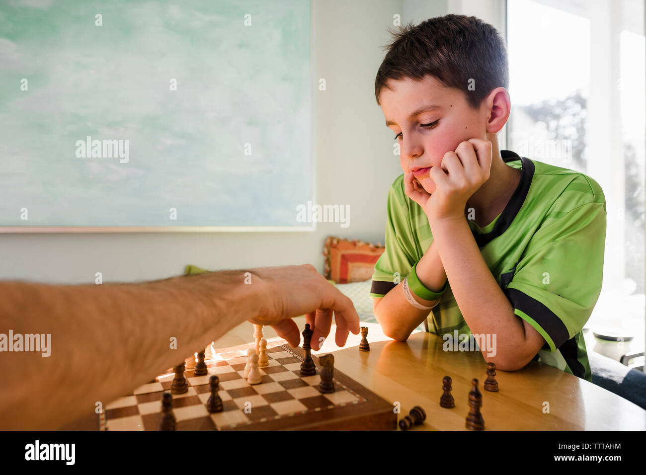 La main coupée de père en jouant aux échecs avec des fils sur la table à la maison Banque D'Images