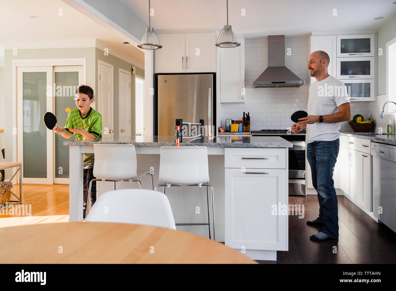 Fils à jouer au tennis de table avec le père sur l'île de cuisine à la maison Banque D'Images