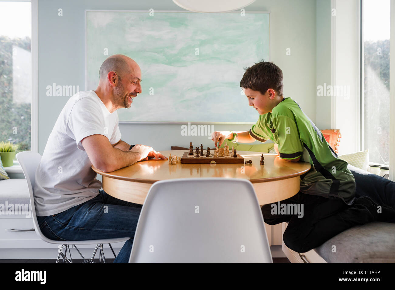 Vue latérale du père avec son fils jouer aux échecs sur le tableau à la maison Banque D'Images