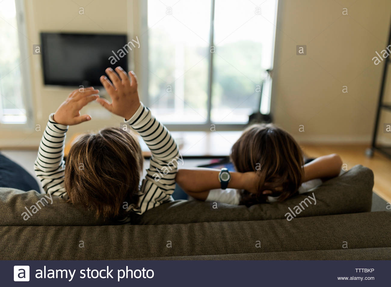 Deux enfants de dos assis sur le canapé à jouer avec une tablette Banque D'Images
