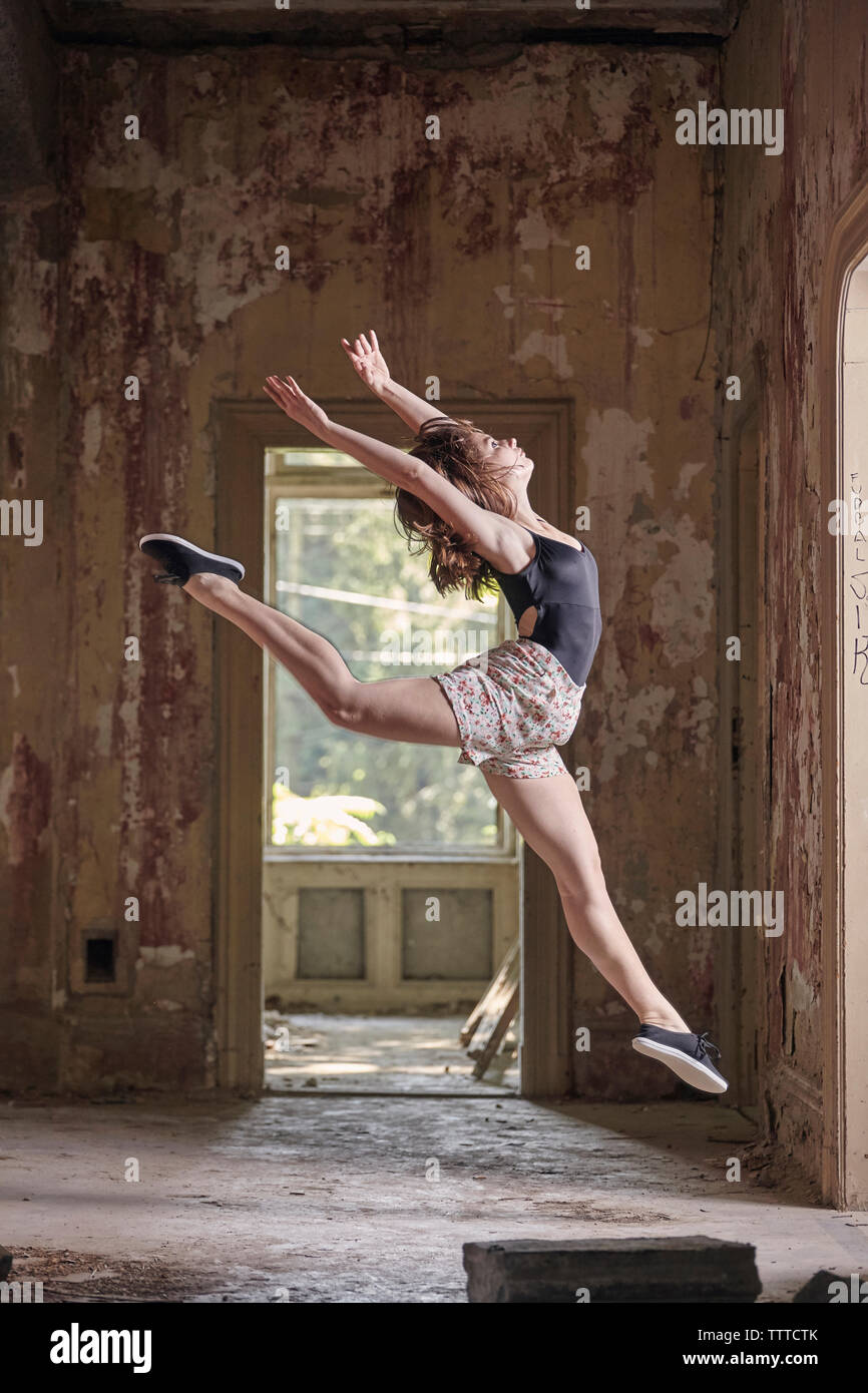 Vue latérale du jeune femme sautant tout en pratiquant le ballet dans l'ancien bâtiment Banque D'Images