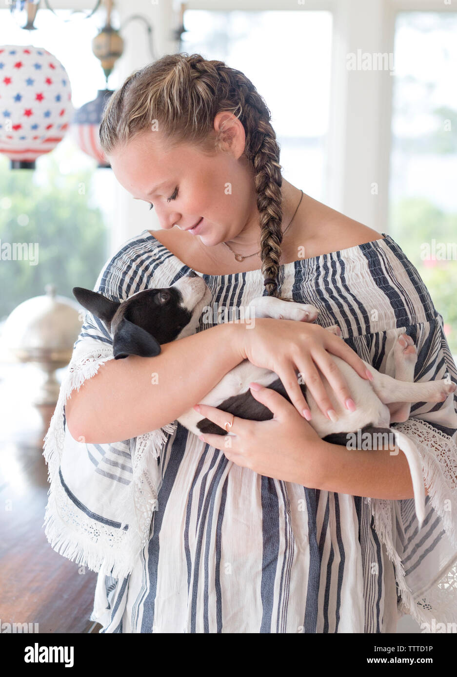 Teen girl with braids holding et à la recherche à l'intérieur sur le coût de chiot Banque D'Images