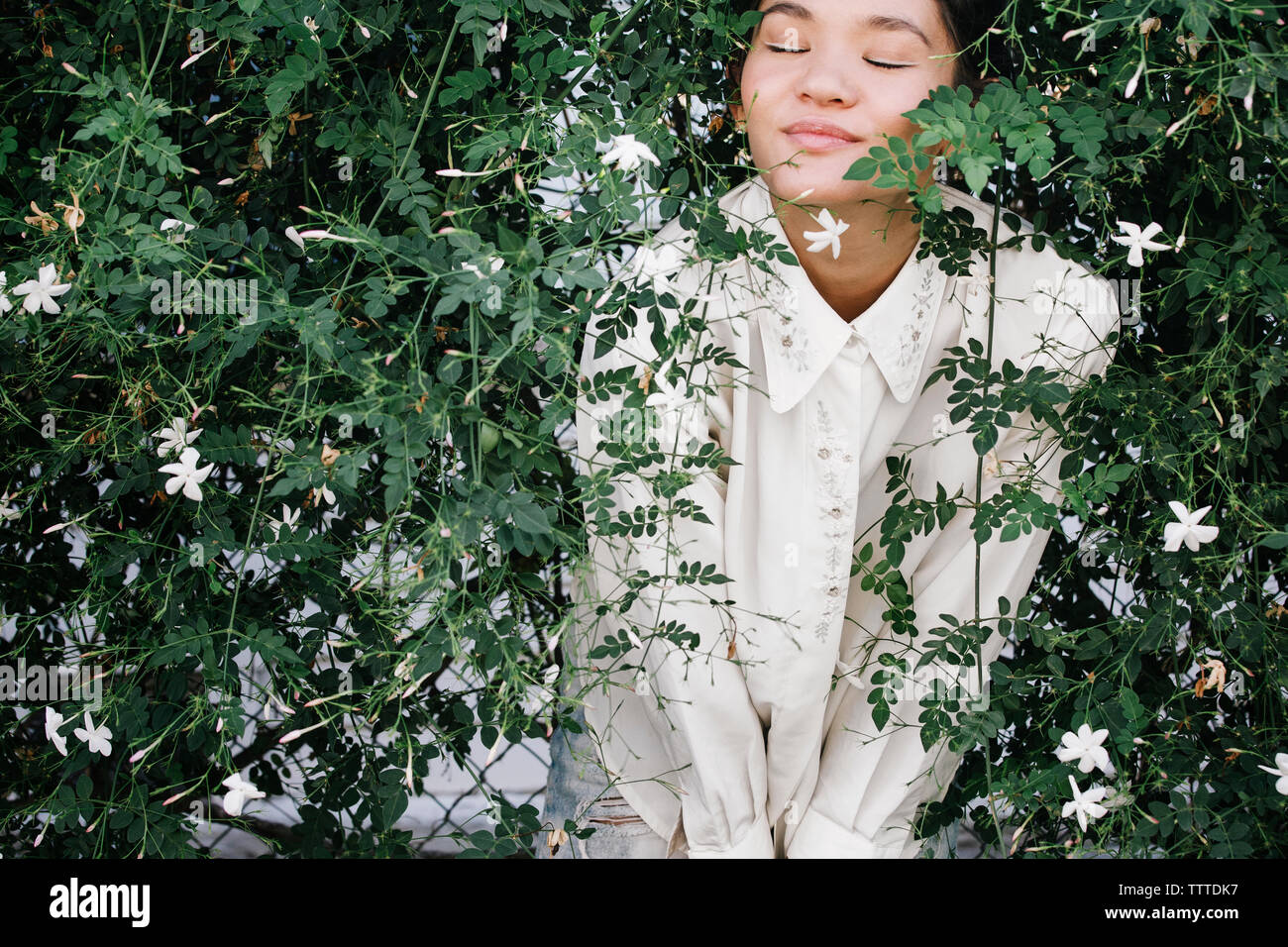 Femme debout détendue avec les yeux fermés au milieu de plantes de jardin Banque D'Images