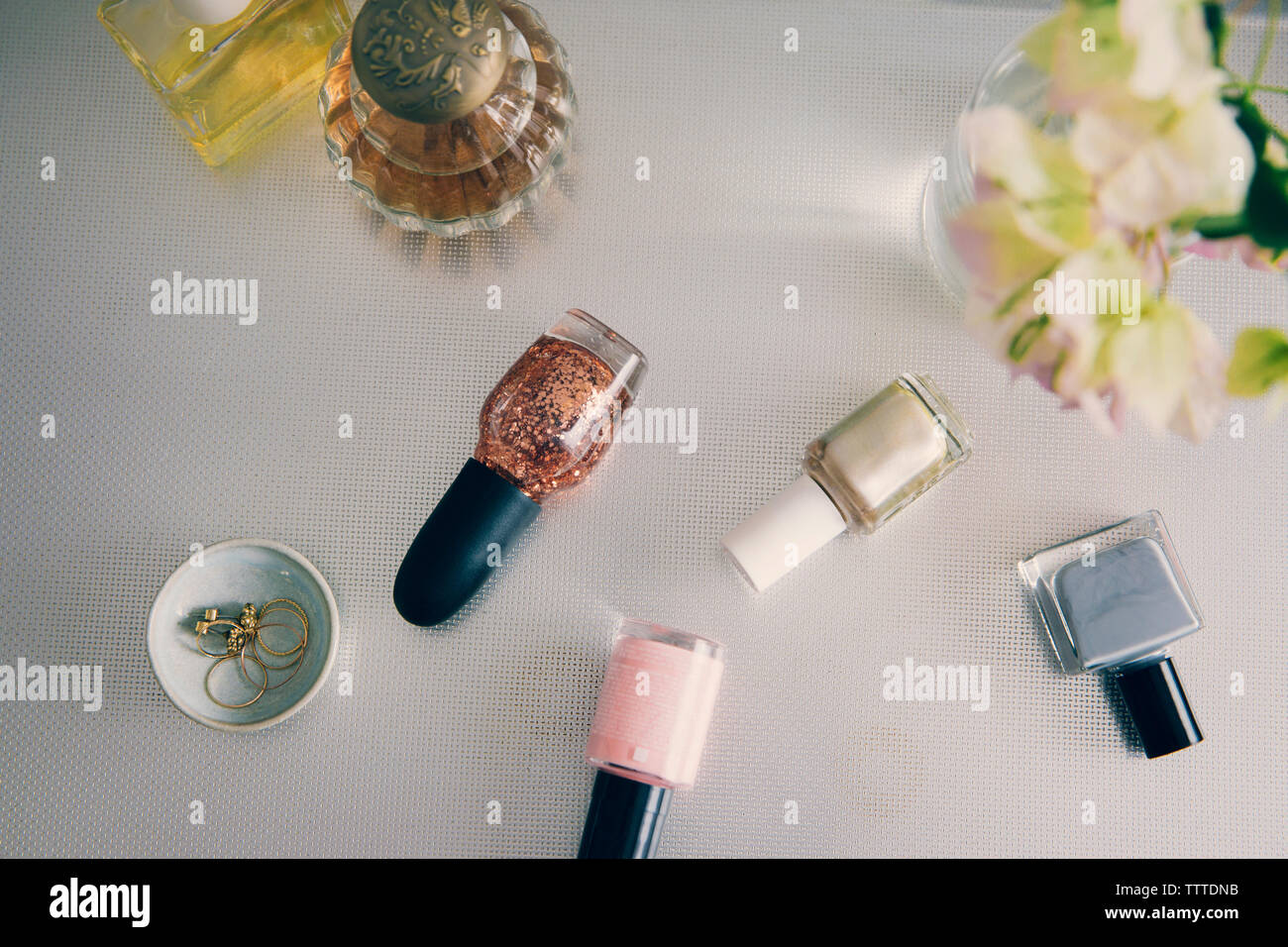Portrait de produits de beauté avec des bijoux par vase à fleurs sur table Banque D'Images