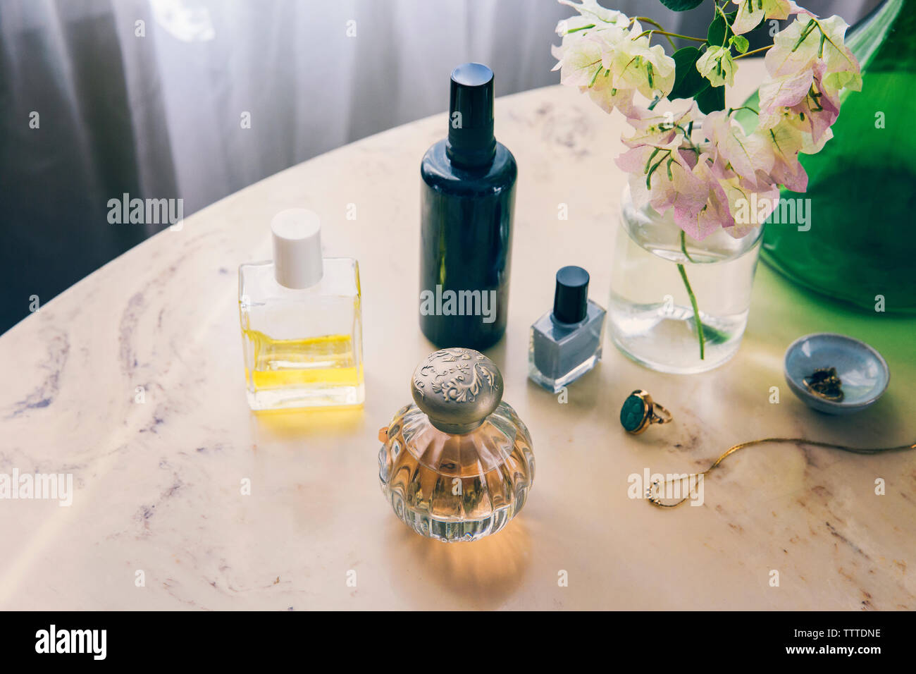 Portrait de produits de beauté avec des bijoux par vase à fleurs sur table Banque D'Images