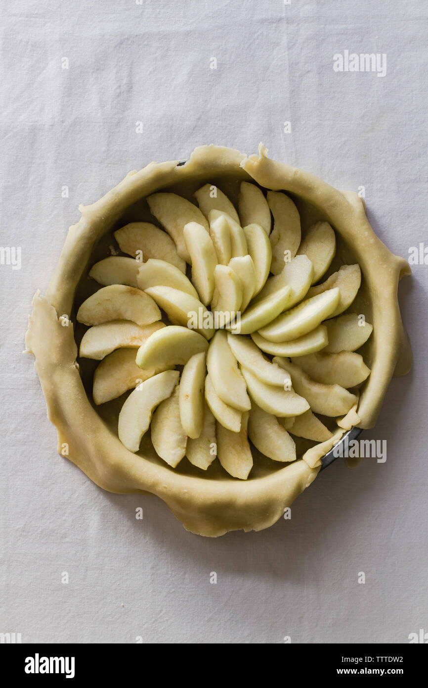 Vue de dessus de tranches de pommes dans la pâte à tarte sur le tableau Banque D'Images