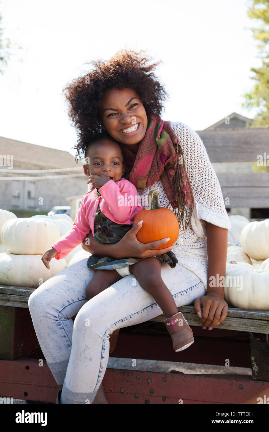 Happy mother holding pumpkin en position assise avec sa fille sur la table Banque D'Images