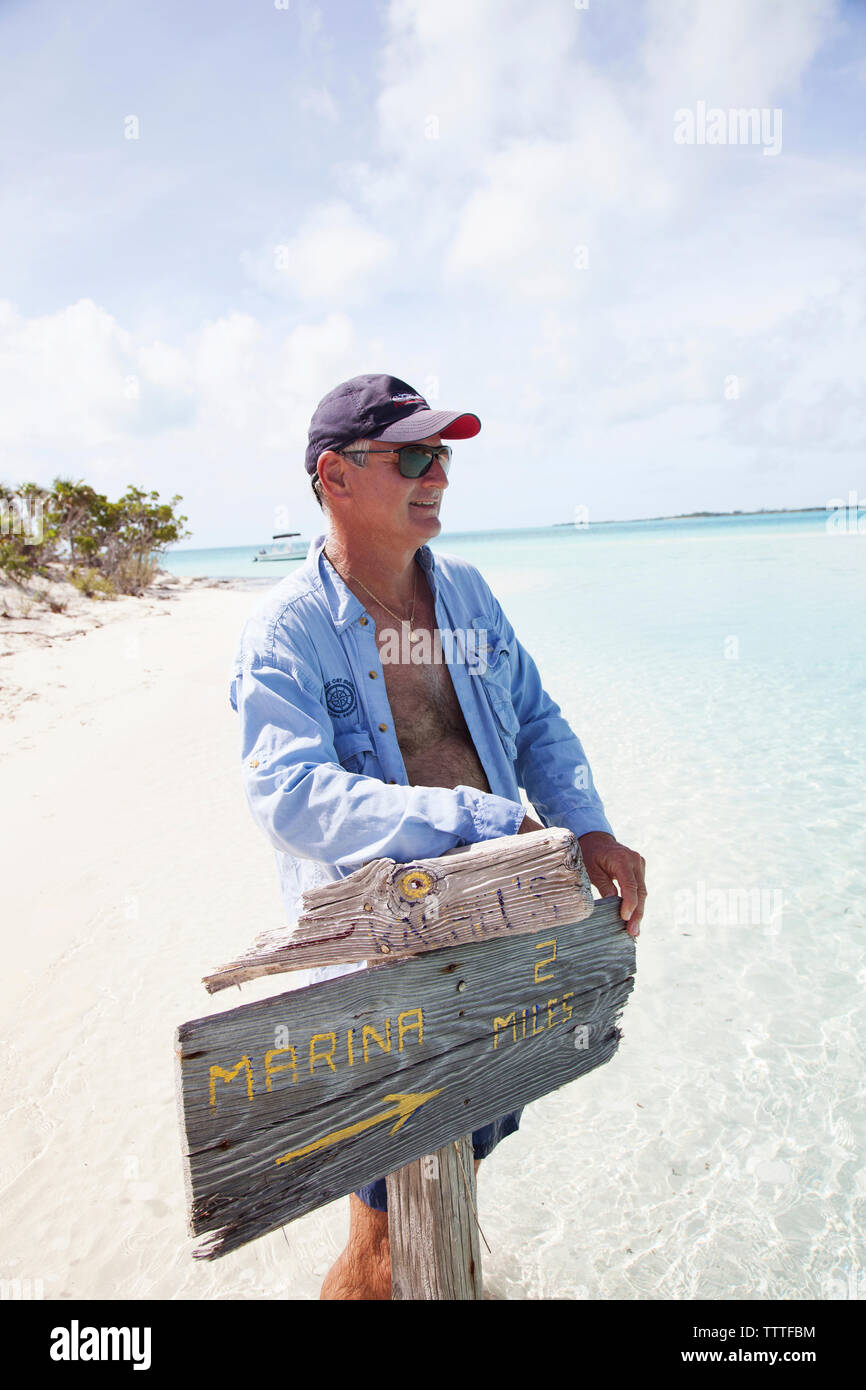 EXUMA, Bahamas. Yves, tenant une pancarte sur Boussole Cay. Banque D'Images