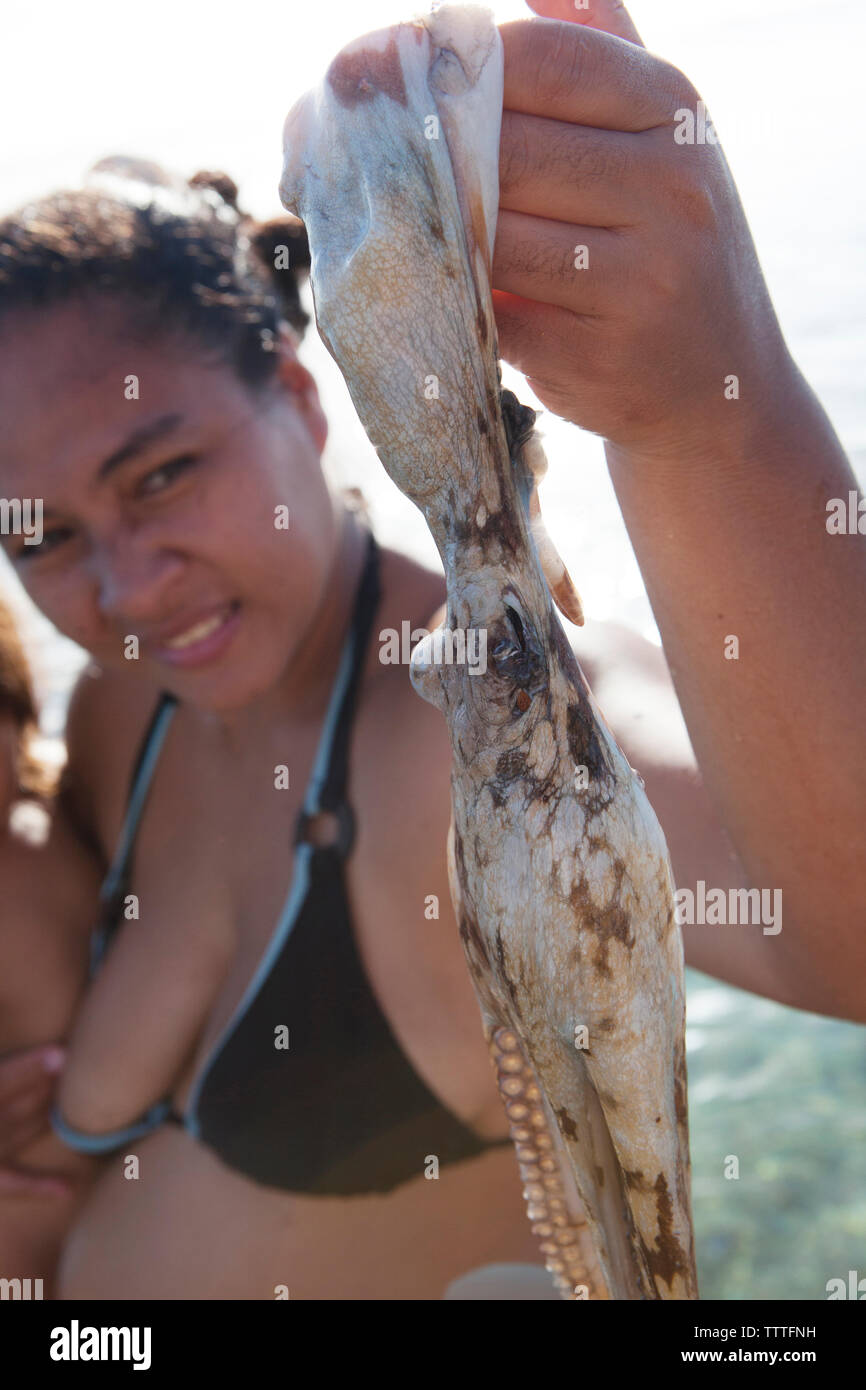 L'île de Raiatea, Polynésie française. Une femme avec son enfant tenant une pieuvre. Banque D'Images