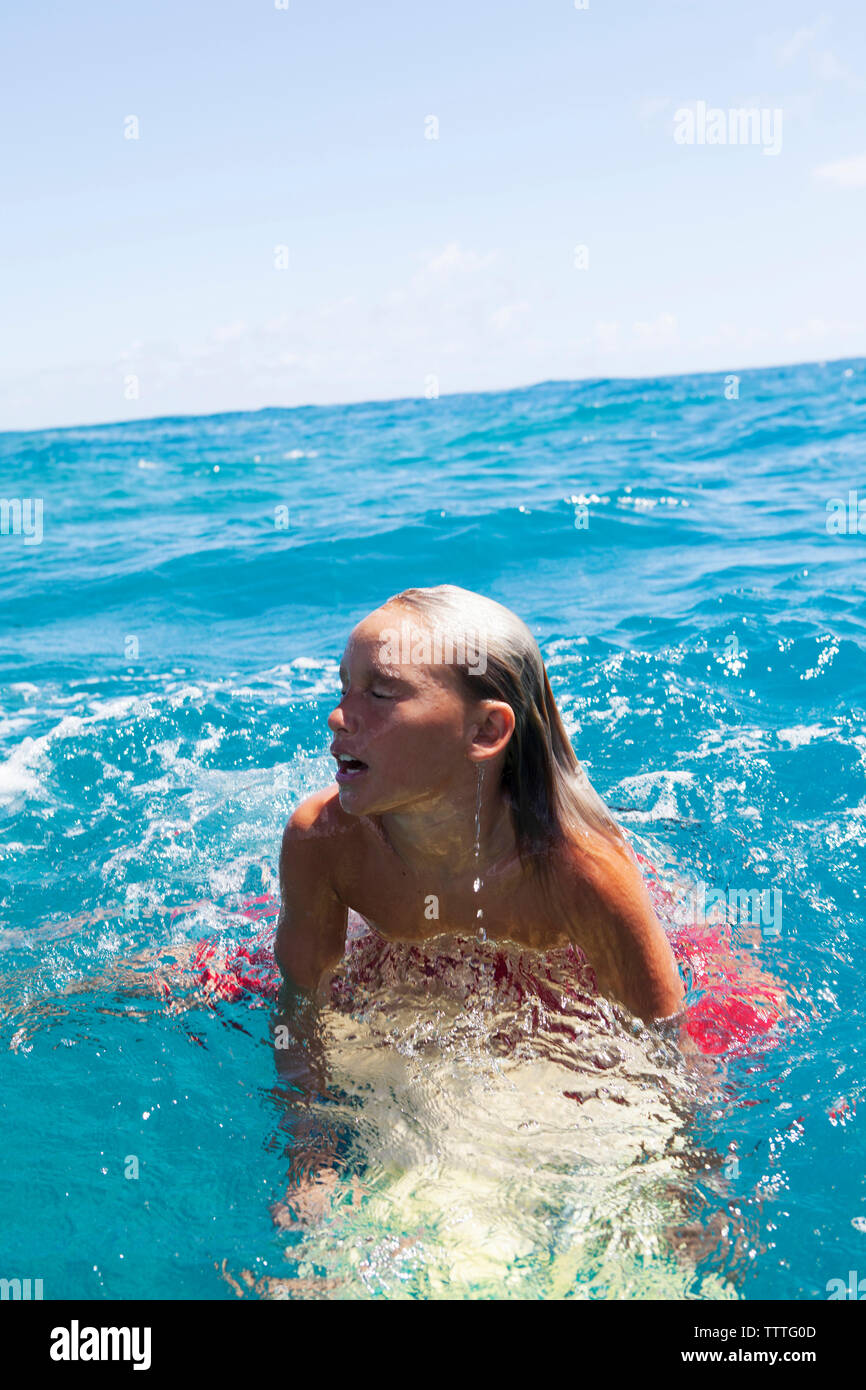 Moorea, Polynésie française. Un jeune garçon, surfeur local dans l'eau. Banque D'Images