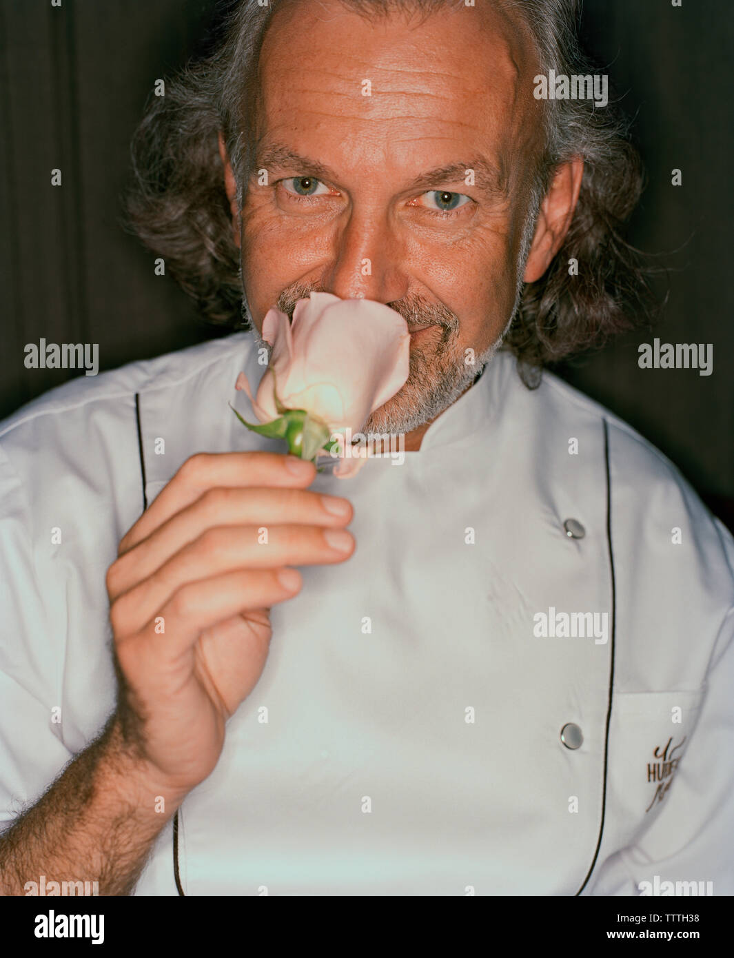 USA, Nevada, Chef Hubert Keller smelling pink flower, close-up, portrait Banque D'Images