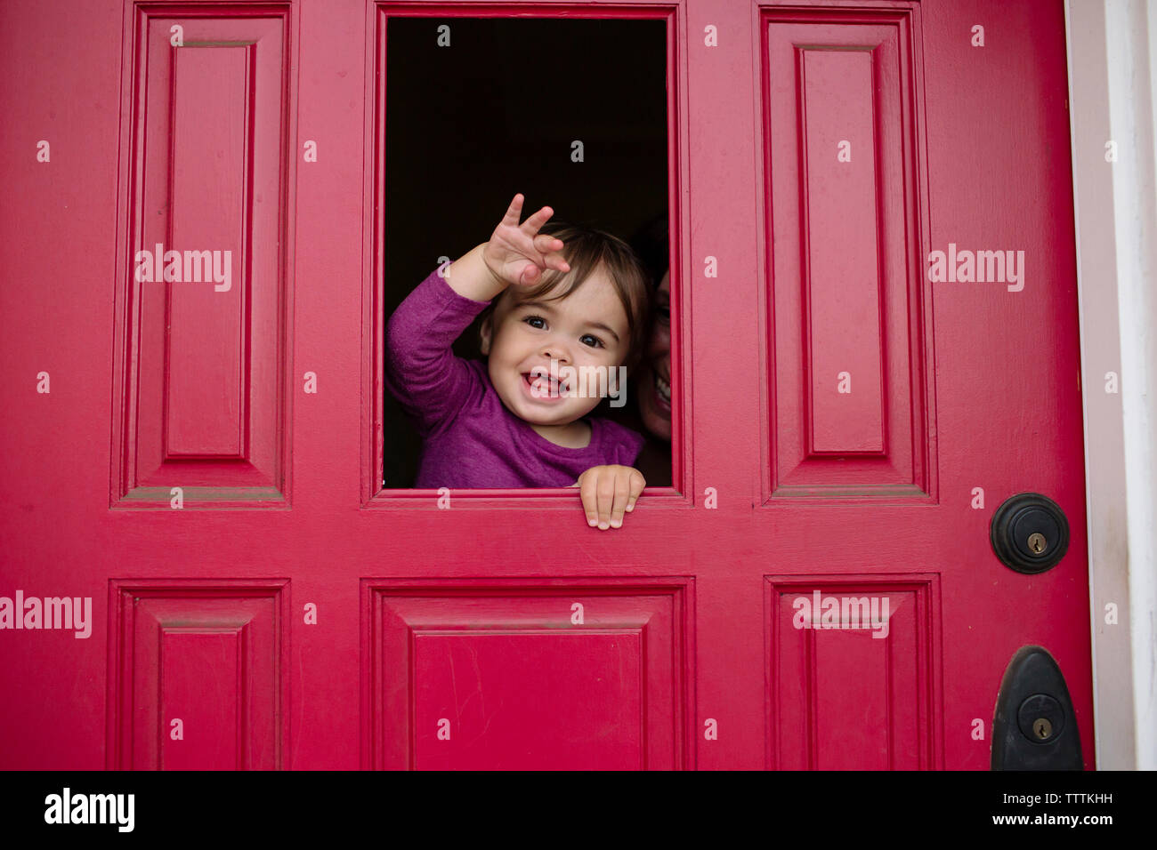 Portrait de fille joyeuse à la mère à travers la vitre avec Banque D'Images