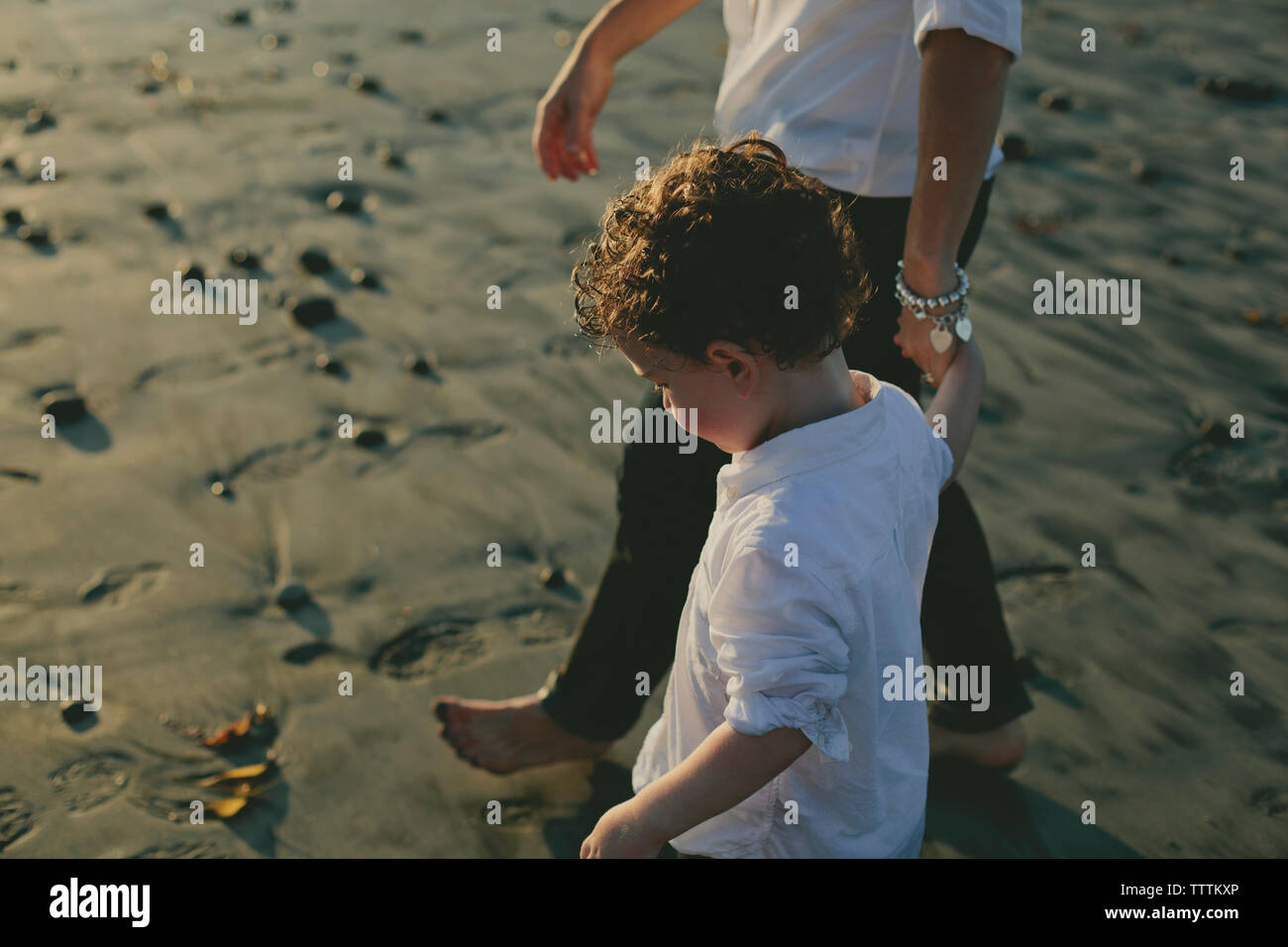 Portrait de son holding mother's hand en marchant at beach Banque D'Images