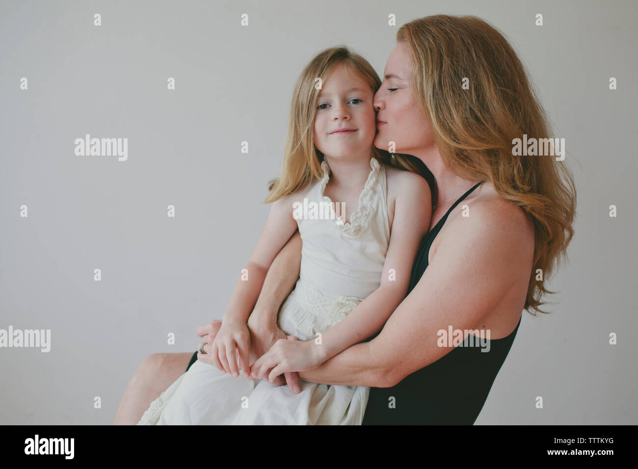 Portrait de fille avec la mère de l'embrasser contre fond blanc Banque D'Images