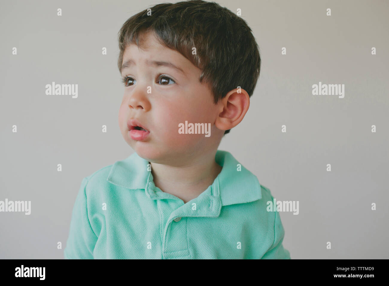 Bébé garçon attentionné à l'extérieur contre fond gris Banque D'Images