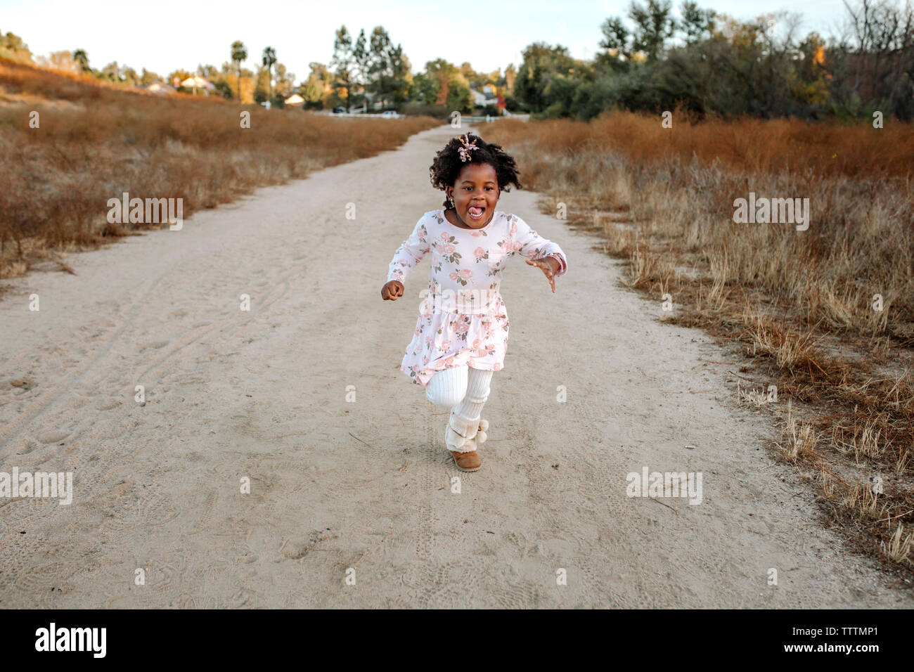 Playful girl running on dirt road in forest Banque D'Images