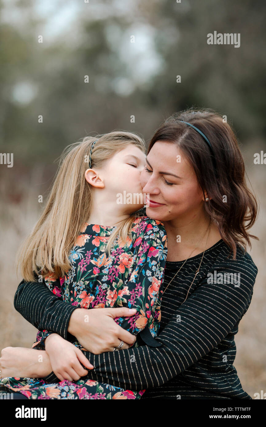Fille mère embrasser tout en restant assis sur les champs Banque D'Images