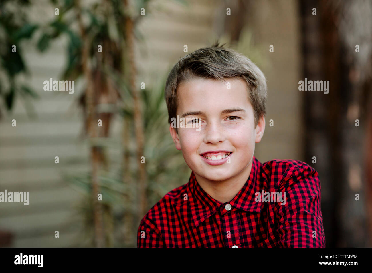 Close-up portrait of smiling boy standing against wall at yard Banque D'Images