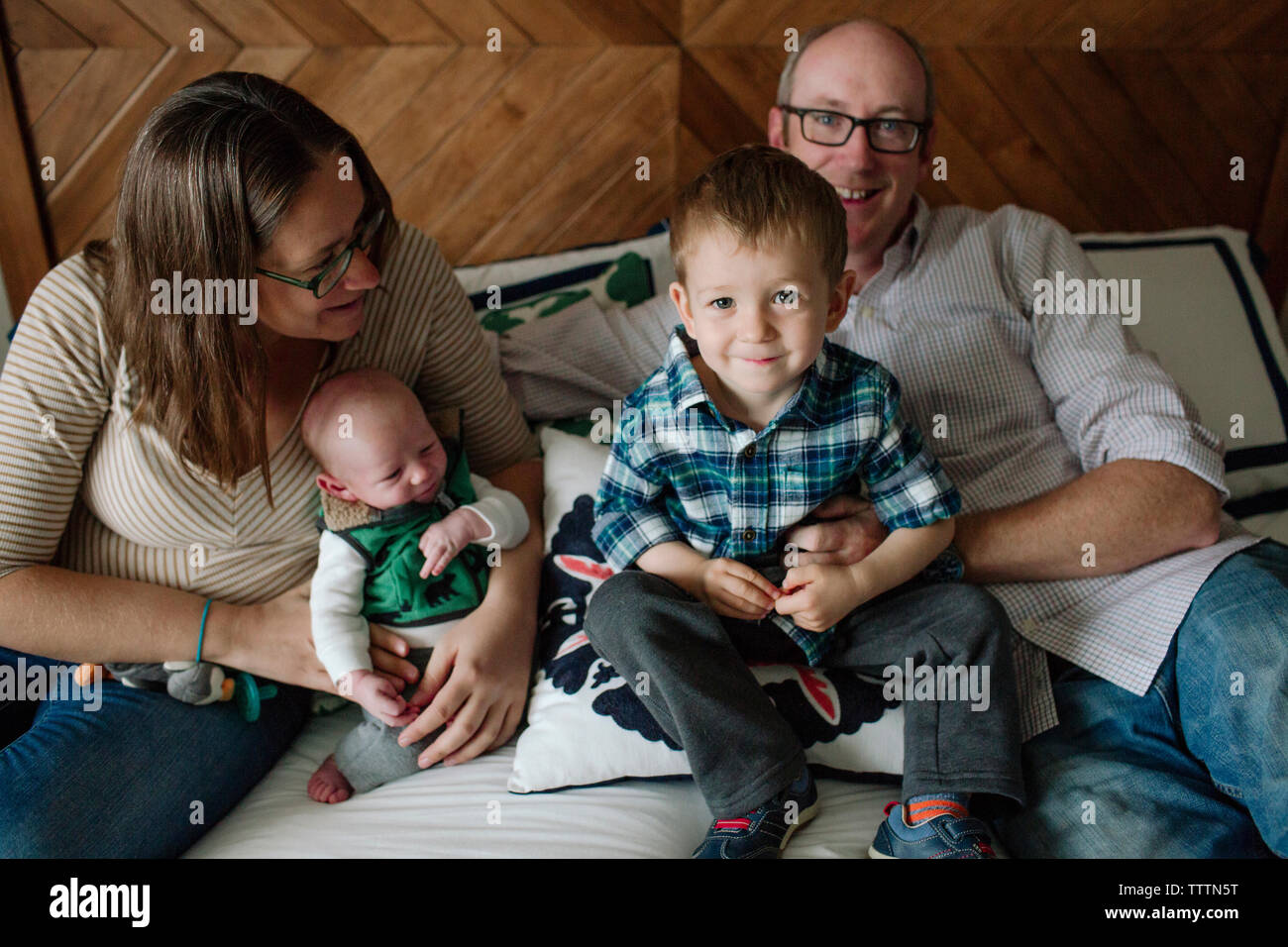 Famille heureuse avec nouveau-né garçon reposant sur le lit chez lui Banque D'Images