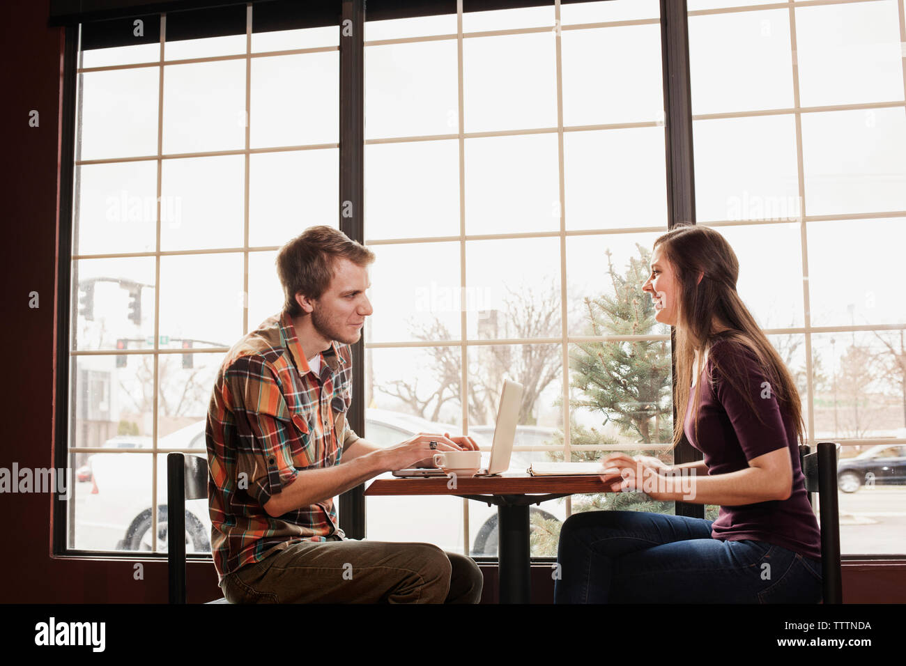 Happy friends sitting at coffee shop par fenêtre Banque D'Images