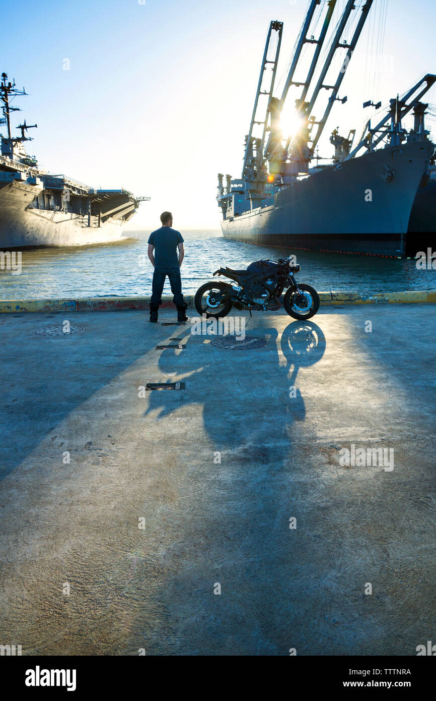 Vue arrière de l'homme debout avec moto sur route à commercial dock Banque D'Images