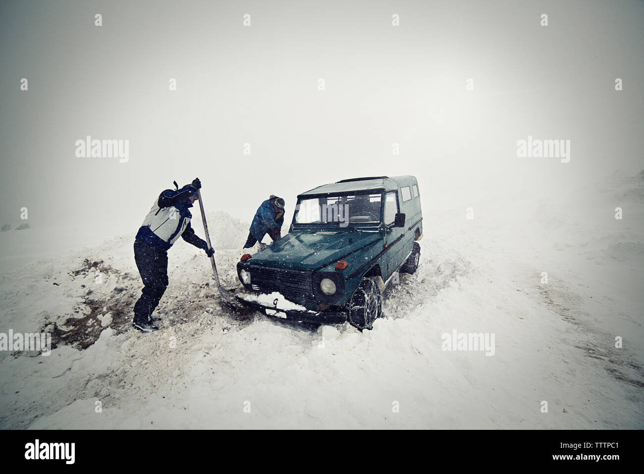 Les hommes enlever la neige avec une pelle en voiture Banque D'Images