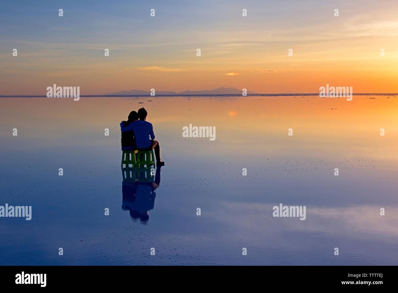 Un couple regardant la télévision sel au coucher du soleil, Salar de Uyuni, Potosi, Bolivie Ministère Banque D'Images