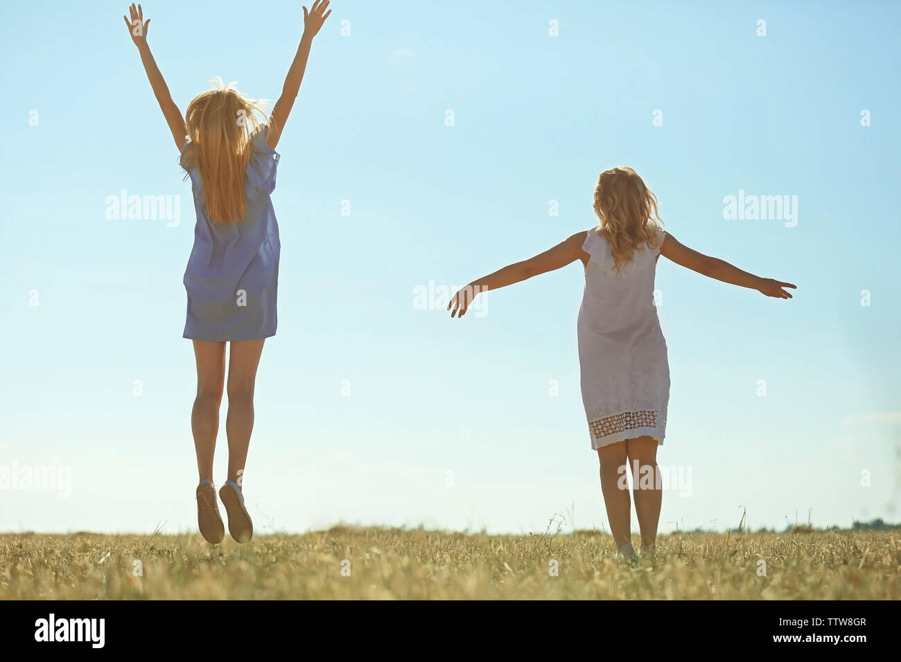Deux funny girls sautant sur fond de ciel bleu Banque D'Images
