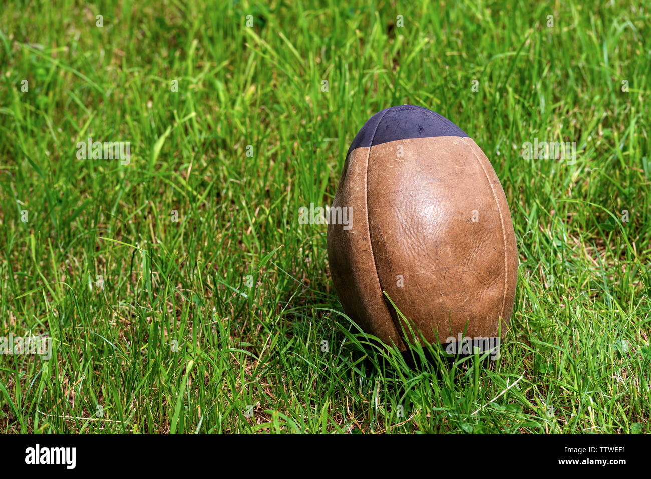 Close-up d'un vieux brun et noir ballon de rugby sur l'herbe verte Banque D'Images