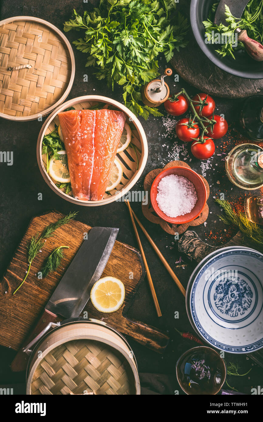 Cuisine asiatique authentique préparation cuisson avec du saumon,assaisonnement, épices, bols et baguettes sur la table de cuisine sombre, vue du dessus. Différents ingrédients, le SEI Banque D'Images