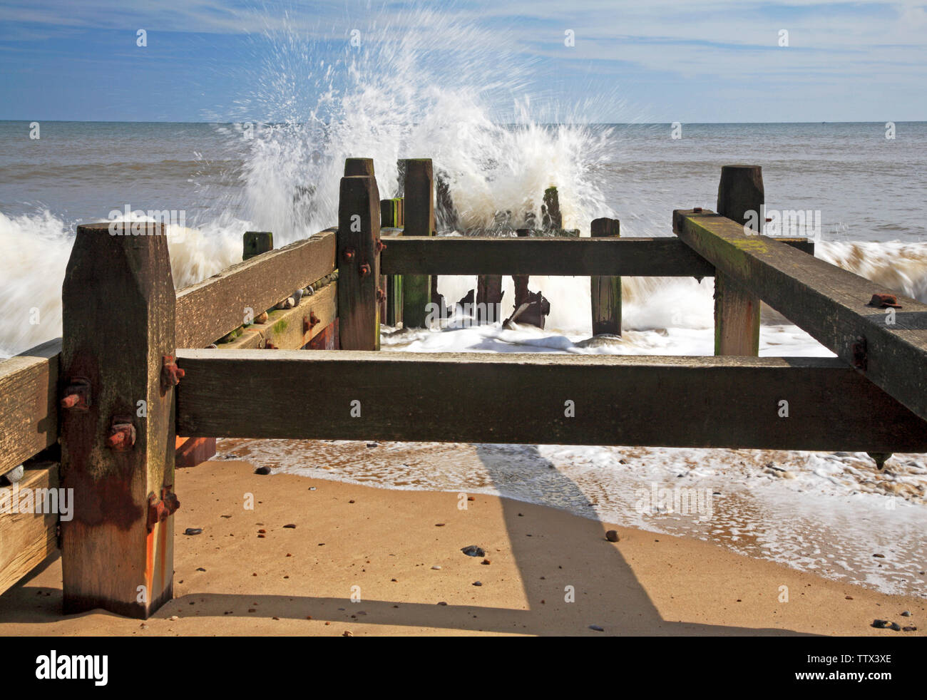 Vue de la mer se briser contre un brise-lames en bois sur la côte de Norfolk à Panier vide, Happisburgh, Norfolk, Angleterre, Royaume-Uni, Europe. Banque D'Images