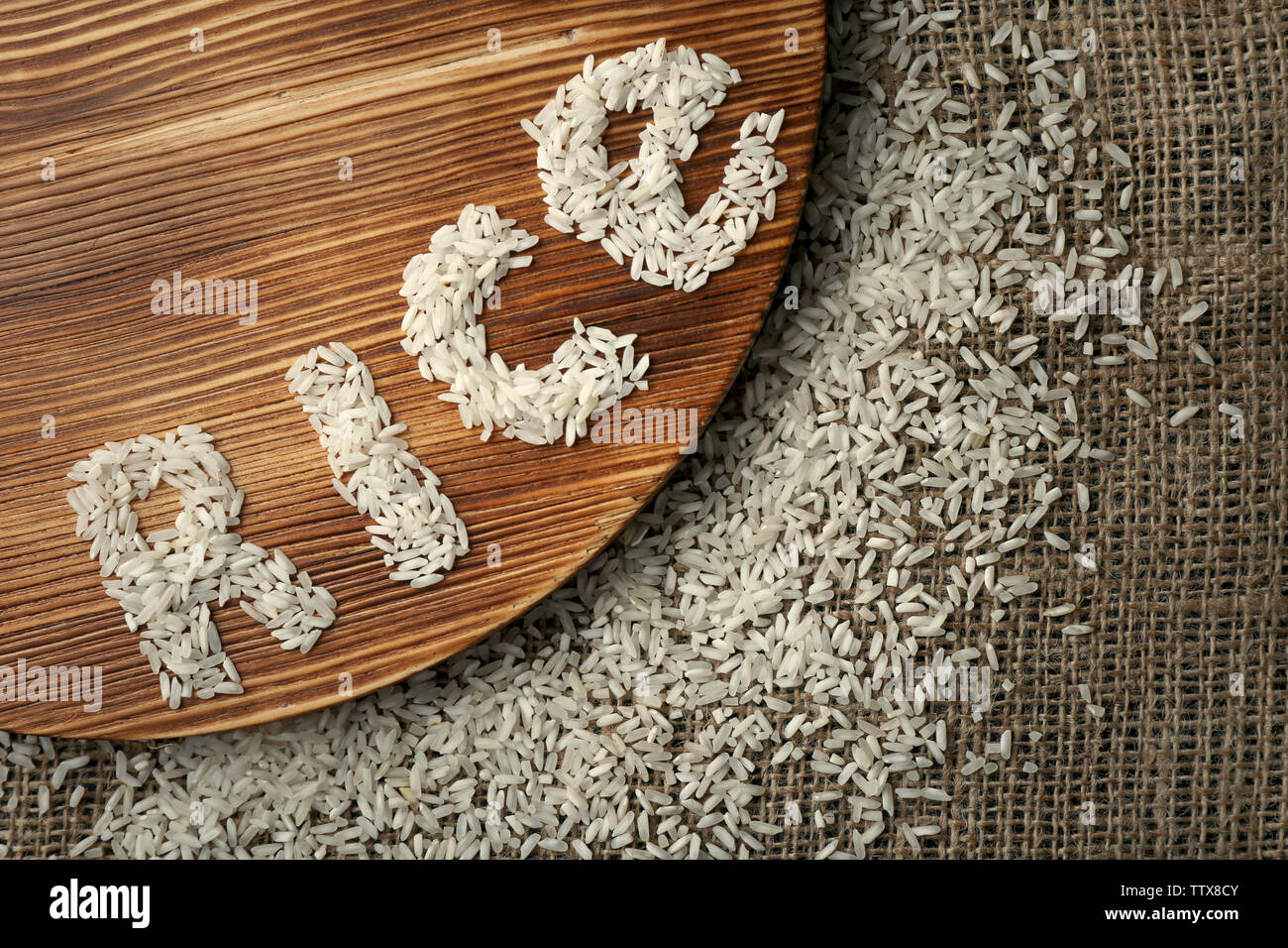 Mot de grains de riz blanc sur planche de bois et un sac, vue d'en haut Banque D'Images