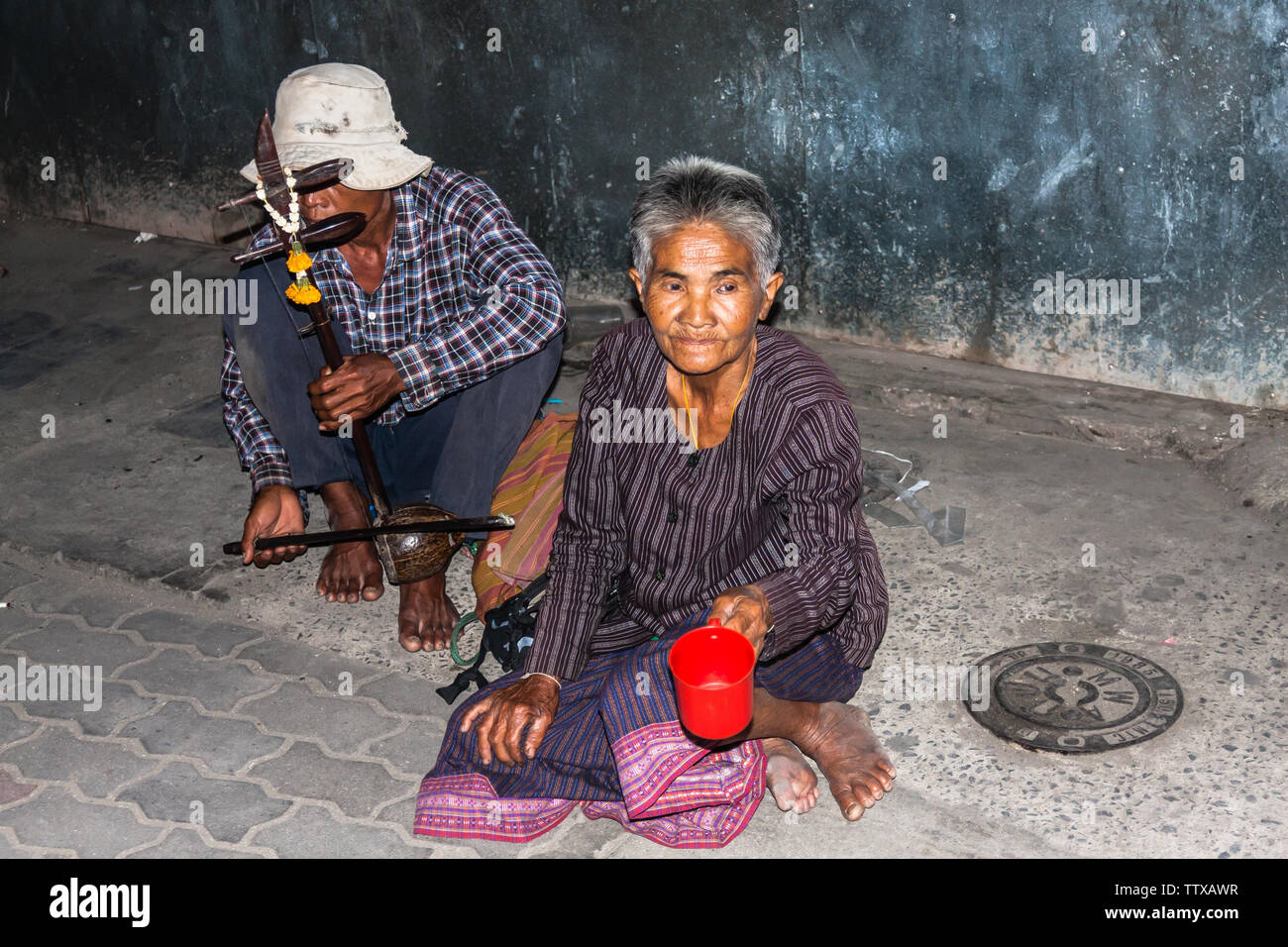Deux personnes adultes la mendicité pour l'argent ou de la nourriture, le mâle joue vu sam sai, un instrument à cordes traditionnel thaïlandais. Bangkok Banque D'Images