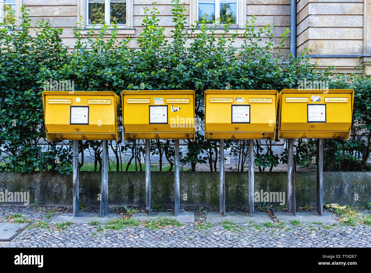 Quatre boîtes aux lettres jaunes pour l'affichage des lettres sur un trottoir en Charlottenburg-Berlin. Banque D'Images