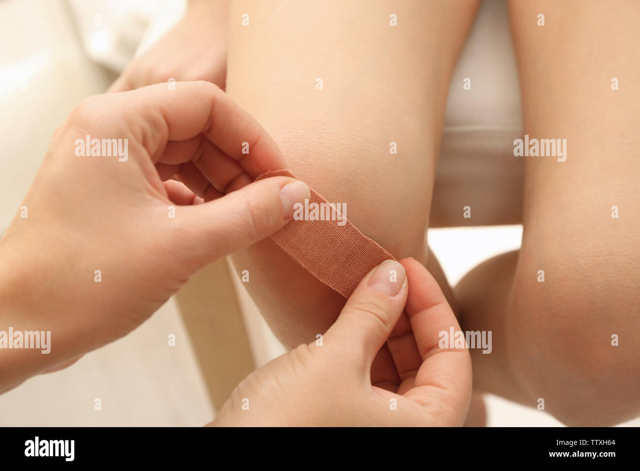 L'application de plâtre sur les mains des femmes girl's knee, gros plan Banque D'Images