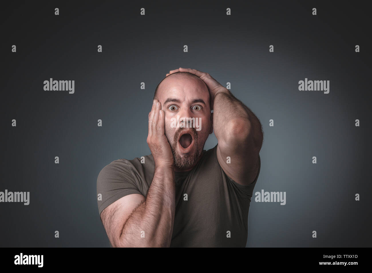 Portrait d'un homme tenant sa tête, l'expression de surprise et de peur. Notion de choc. Banque D'Images