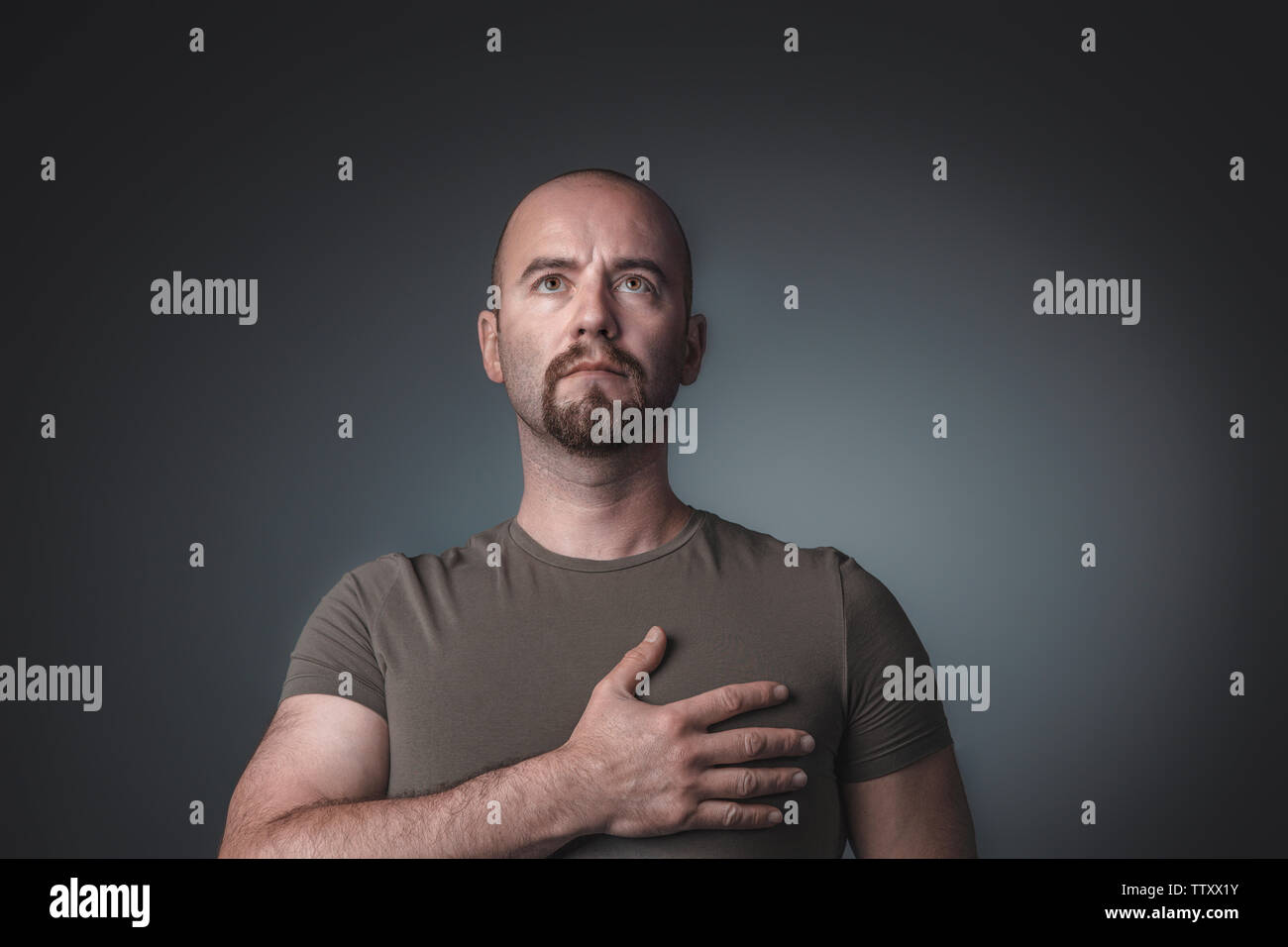 Portrait d'un homme à la recherche et en maintenant une main sur son cœur. L'expression solennelle et fier. Banque D'Images