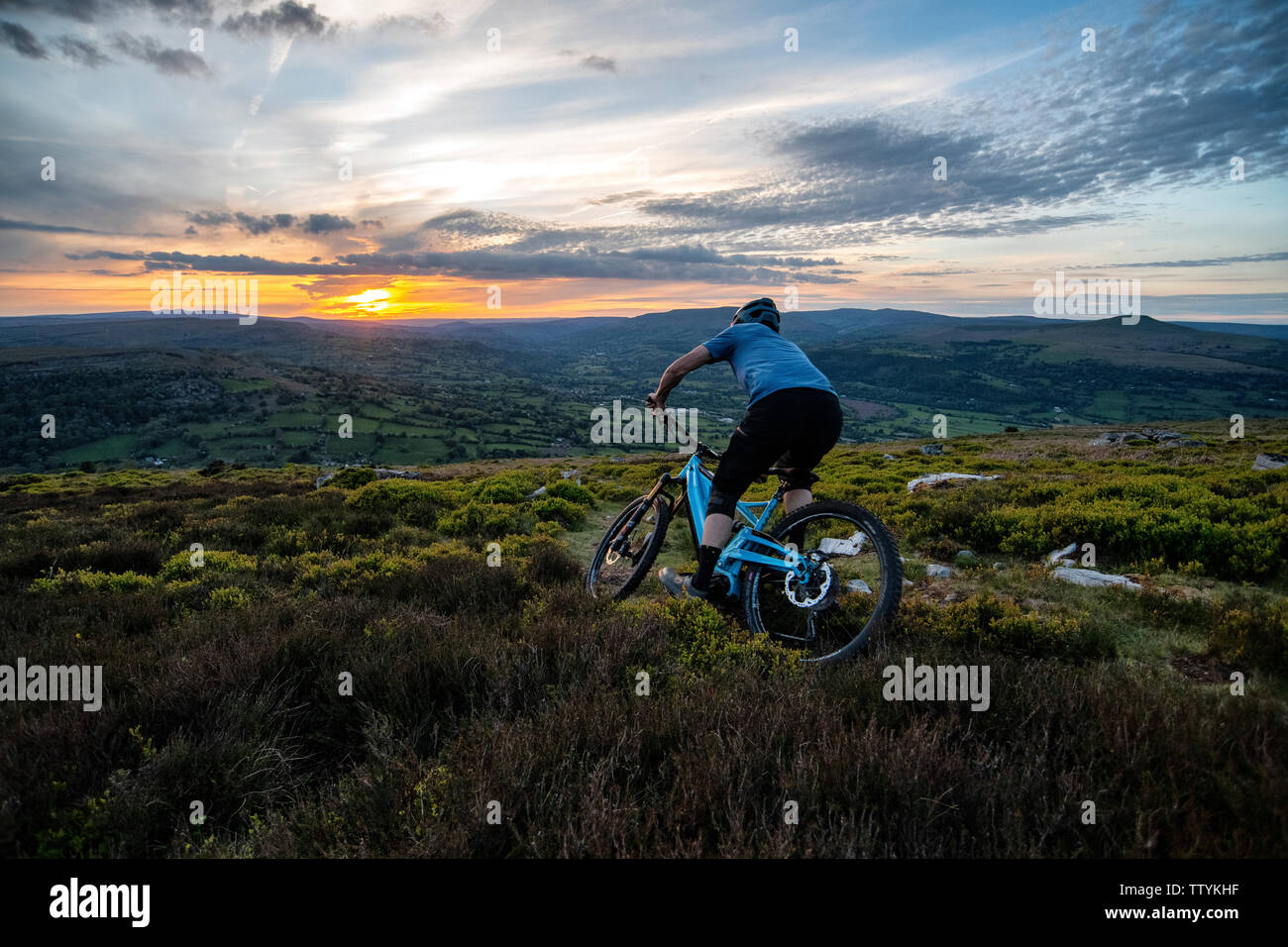 Un homme rides un ebike depuis le sommet de l'Ardanaiseig dans les Brecon Beacons, près d'Abergavenny, Monmouthshire, Wales. Randonnée cycliste du Pays de Galles. Banque D'Images