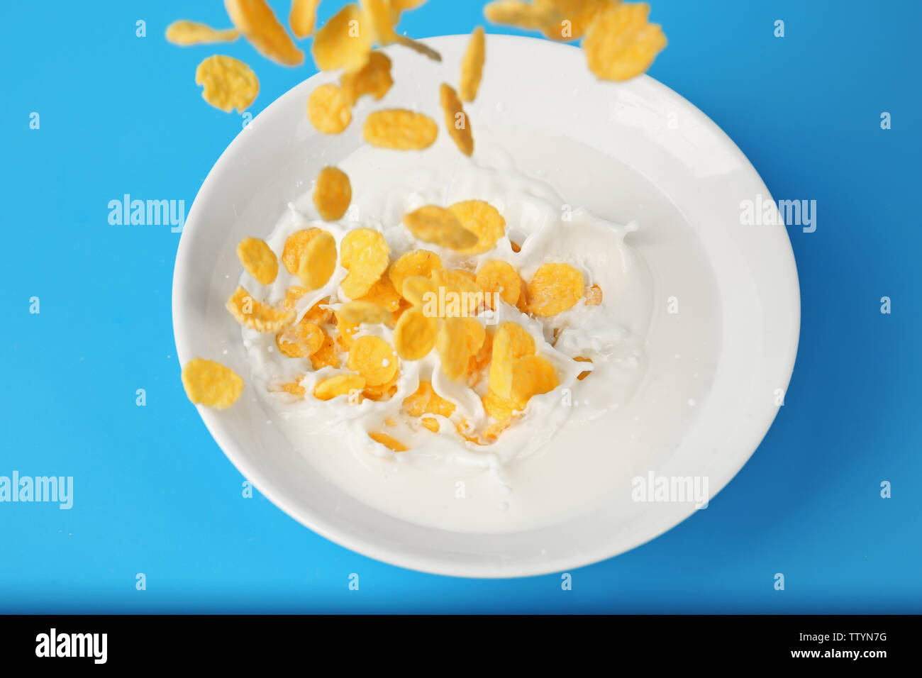 Flocons de maïs avec du lait dans un bol sur fond bleu Banque D'Images