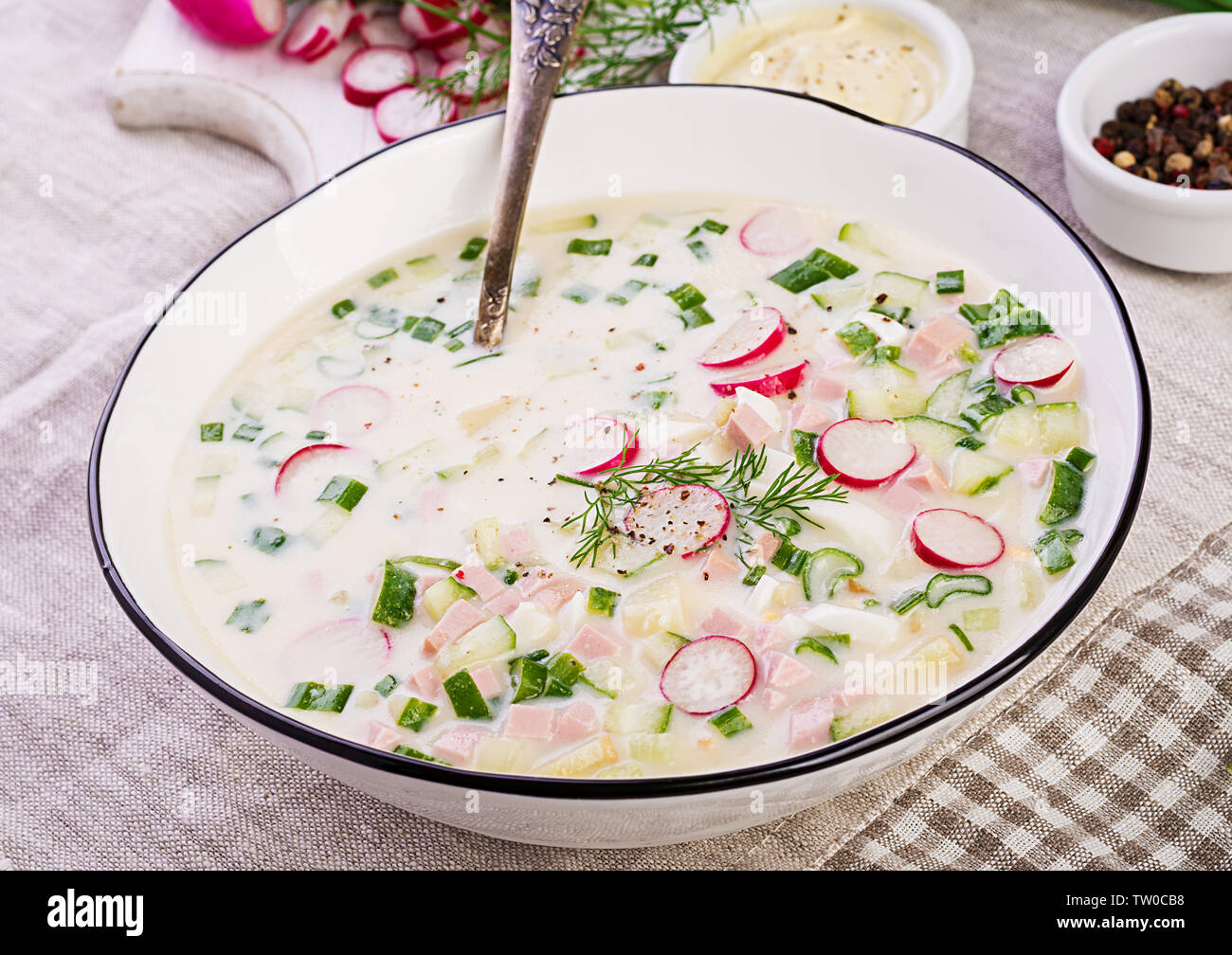 Soupe froide de concombres, radis, pomme de terre et des saucisses avec du yogourt dans un bol. La cuisine russe traditionnelle - okroshka. Soupe froide d'été. Banque D'Images