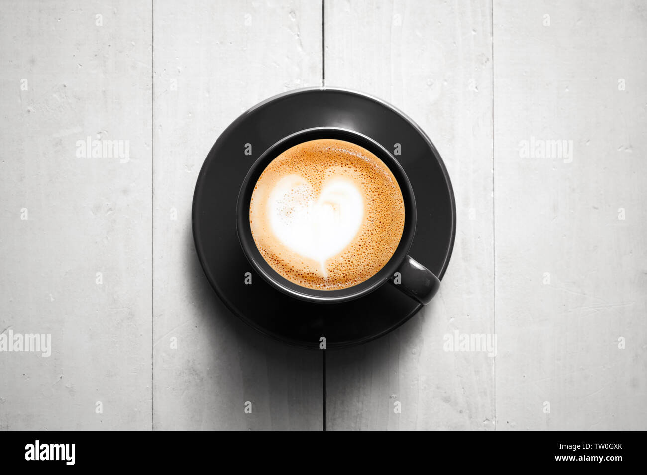Petite tasse de cappuccino noir se dresse sur une table en bois blanc, vue du dessus Banque D'Images
