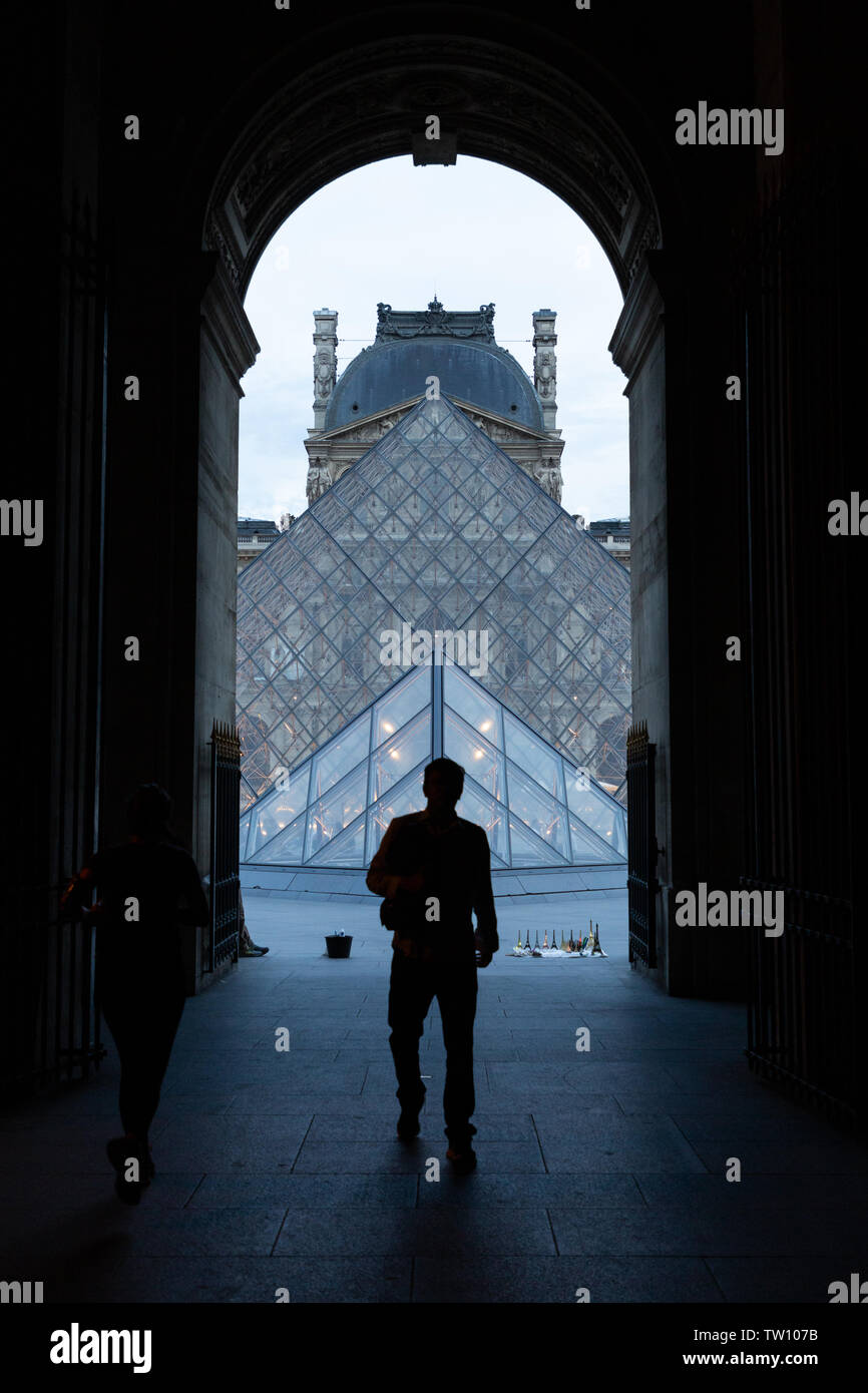 Silhouettes dans une arche à la pyramide du Louvre Banque D'Images