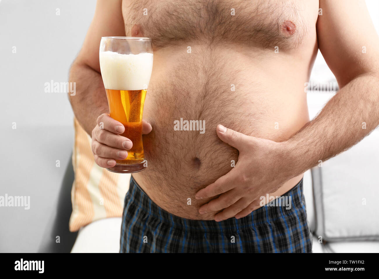 Homme avec gros ventre holding verre de bière à la maison Photo Stock -  Alamy