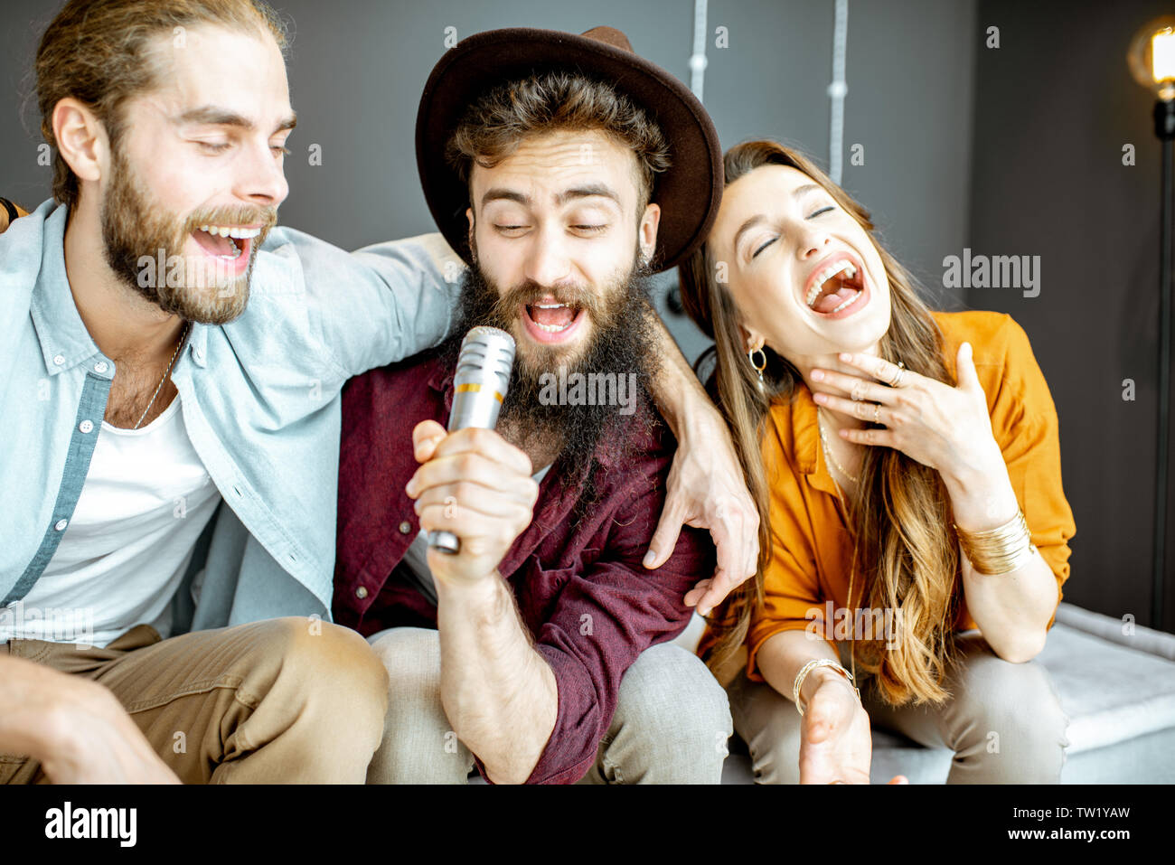 Les jeunes et gaies avec microphone chant d'amis tout en jouant à karaoke at home Banque D'Images