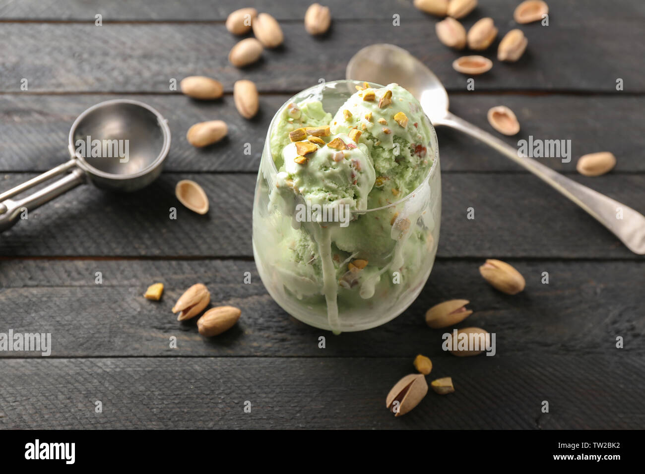 Avec verre fusion délicieuse glace pistache-crème sur fond de bois noir Banque D'Images