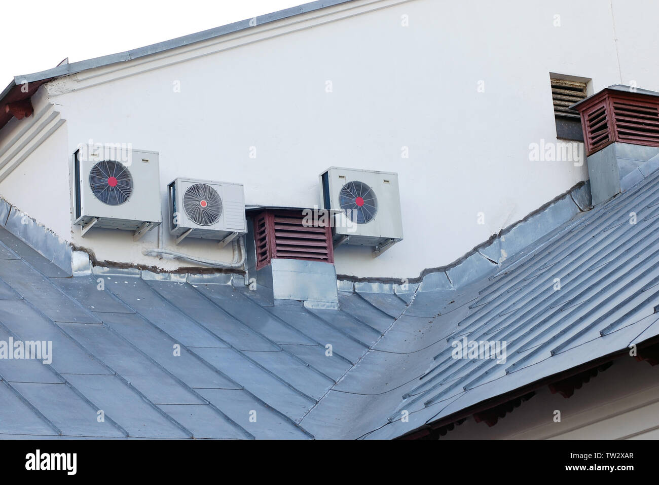 Unités extérieures de climatisation moderne à côté de vieux tuyaux de ventilation sur le toit de maison Banque D'Images